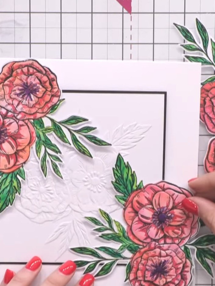 Passo 16: Apply foam pads to the back of the 3D floral embellishments. Position them around the embossed frame on the ca