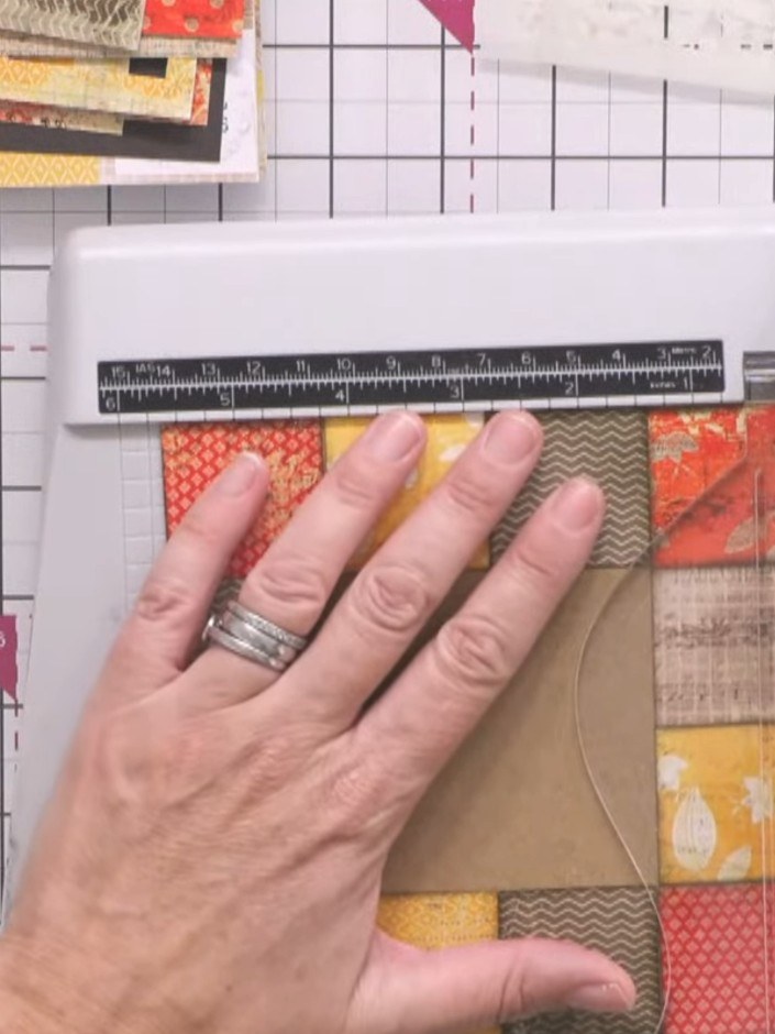 Passo 4: Place the patchwork frame on your paper trimmer and trim the card front to size, keeping the patchwork frame i