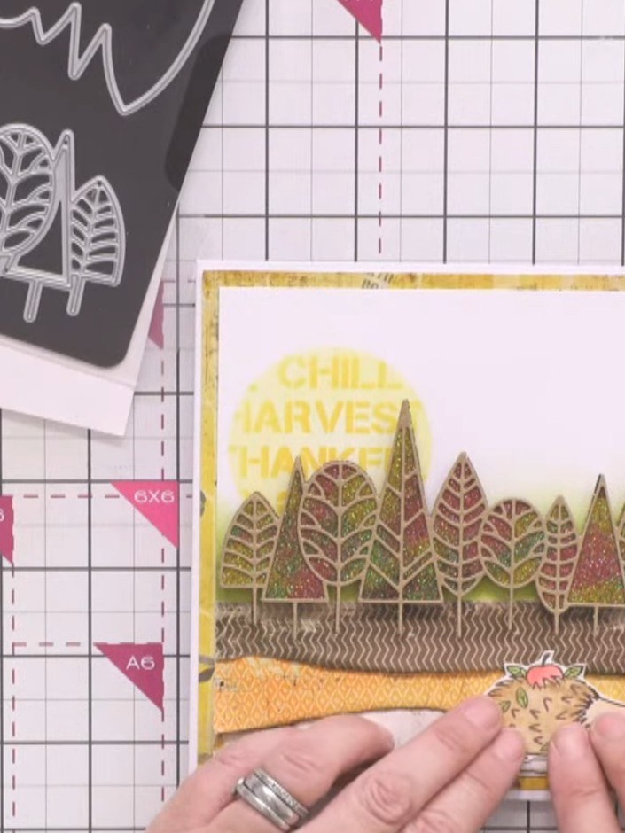 Passo 13: Adhere the stamped and coloured hedgehog character to the lower right foreground of the card, positioning it o