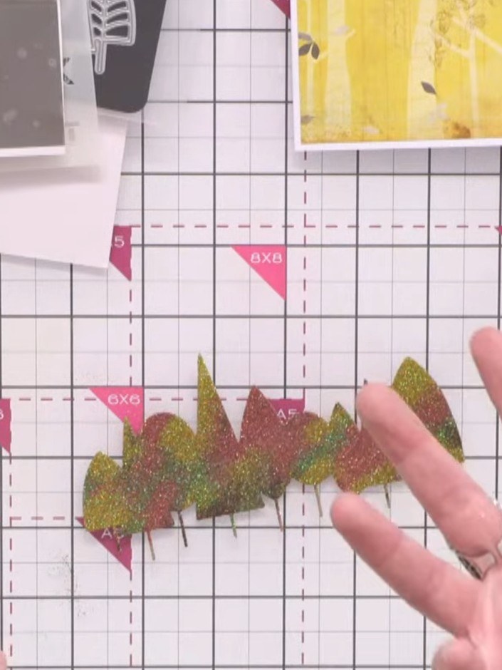 Passo 4: Burnish the glittered tree line pieces between layers of card to ensure the fine glitter adheres completely an