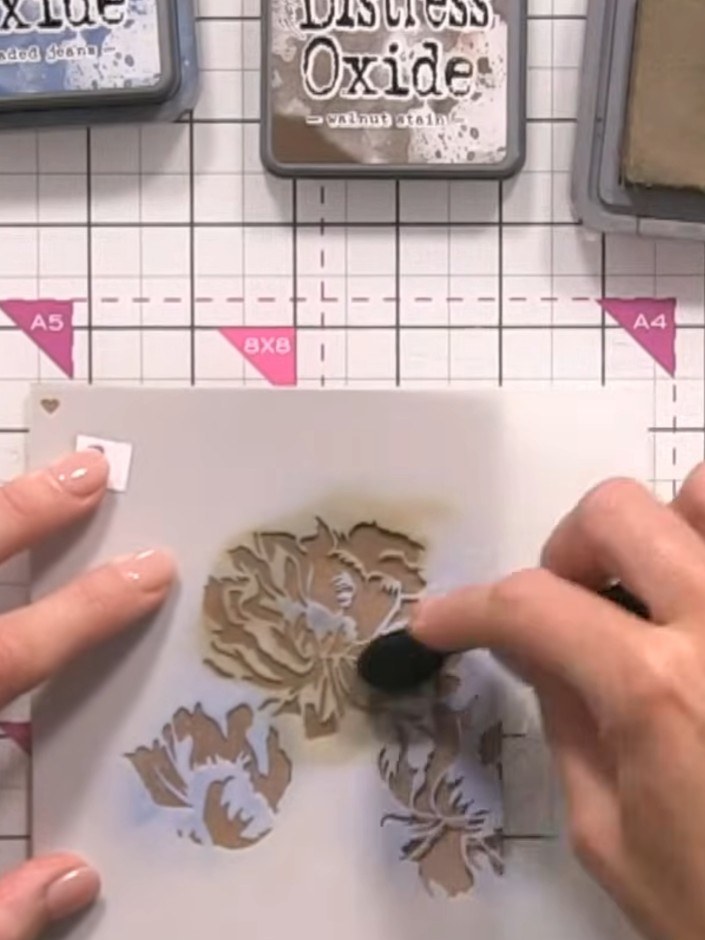 Step 6: Position your second stencil layer aligned with the card edge. Apply the brown Distress Oxide ink with slightl