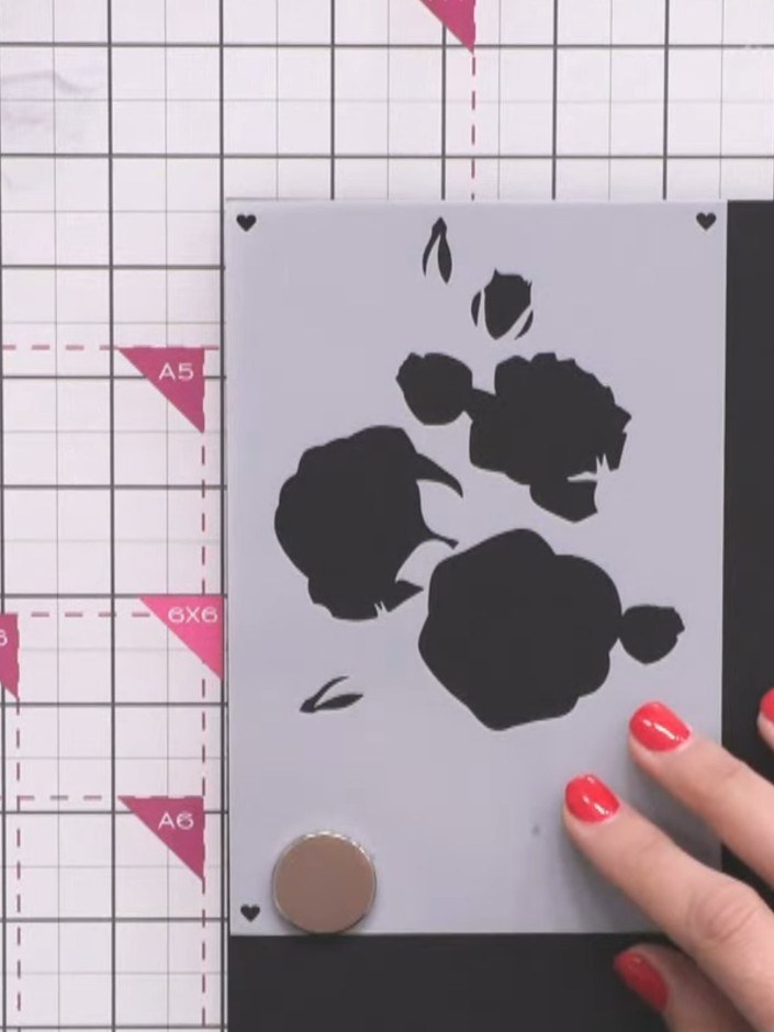 Passo 1: Position the rose stencil in the corner of your card, aligning the registration hearts at the corners. Secure 