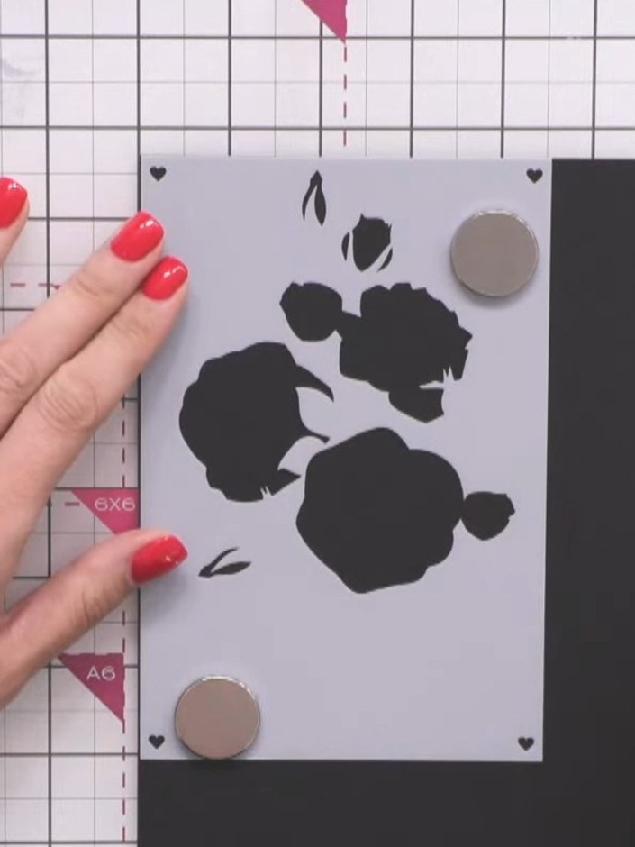 Passo 2: Using a sponge dauber, dab white pigment ink through the rose stencil onto the grey cardstock. Build up the co