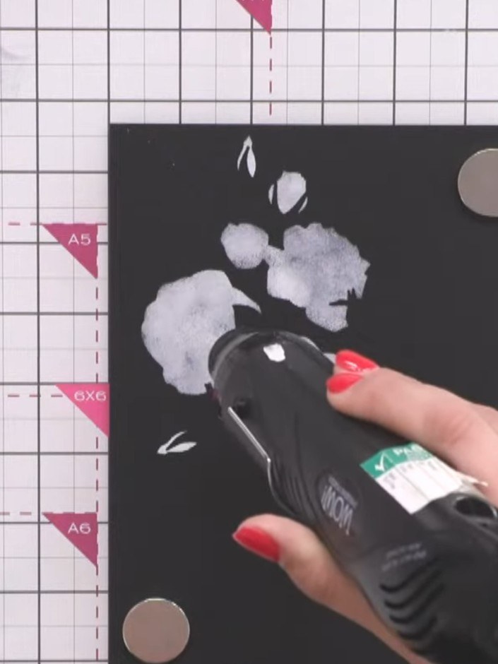 Passo 3: Use a heat gun to dry the first layer of pigment ink thoroughly before applying the next stencil layer. This p
