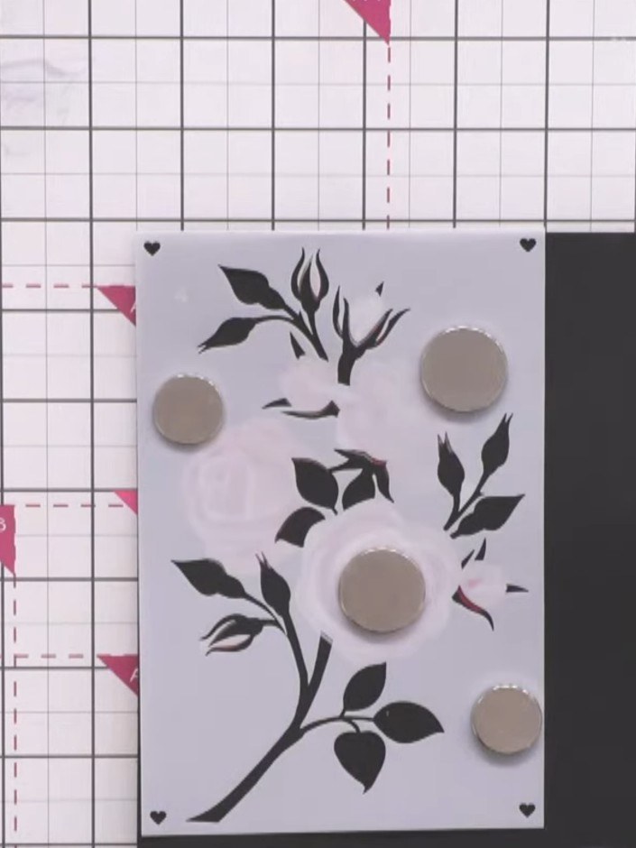 Passo 6: Position four magnets on the fourth stencil layer on the black cardstock. Apply a white pigment ink base layer