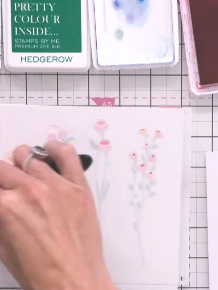 Step 9: Add flower head details using additional stencils. Apply pink and orange colours to create floral embellishmen