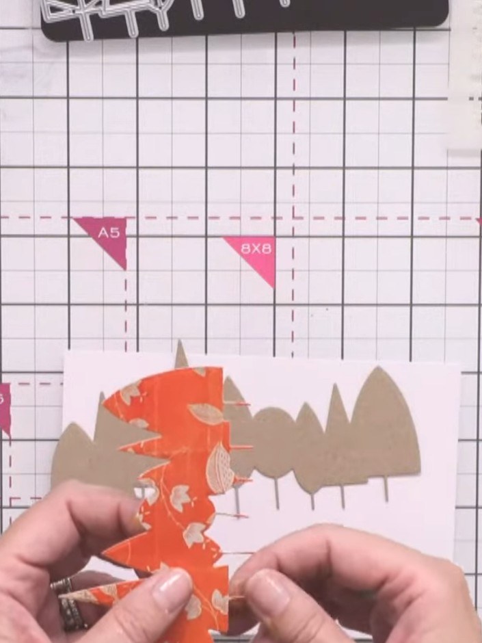 Stap 3: Trim away the tree trunks from the detailed orange overlay die-cut piece to simplify the layering process. Thi