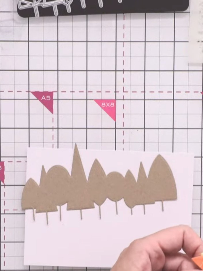 Stap 4: Layer the patterned paper tree line over the craft cardstock base. Add the detailed overlay in dark brown card