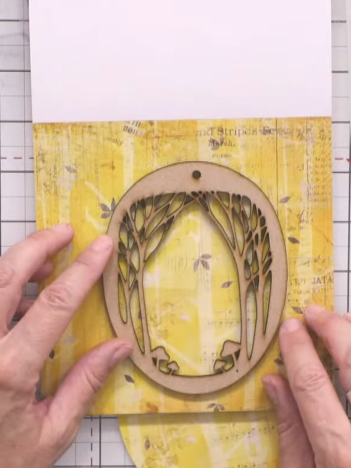 Step 3: Place the MDF tree topper onto the yellow patterned paper background and carefully cut around the pencil outli