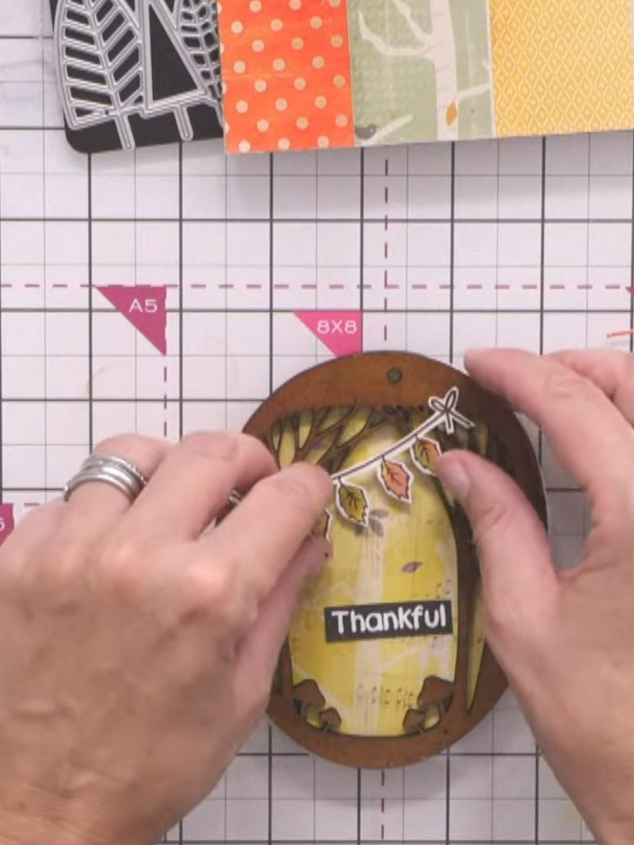Step 9: Stemple das Wort „Thankful“ aus dem Stempelset mit schwarzer Stempelfarbe in die Mitte des gelb verzierten Panels.