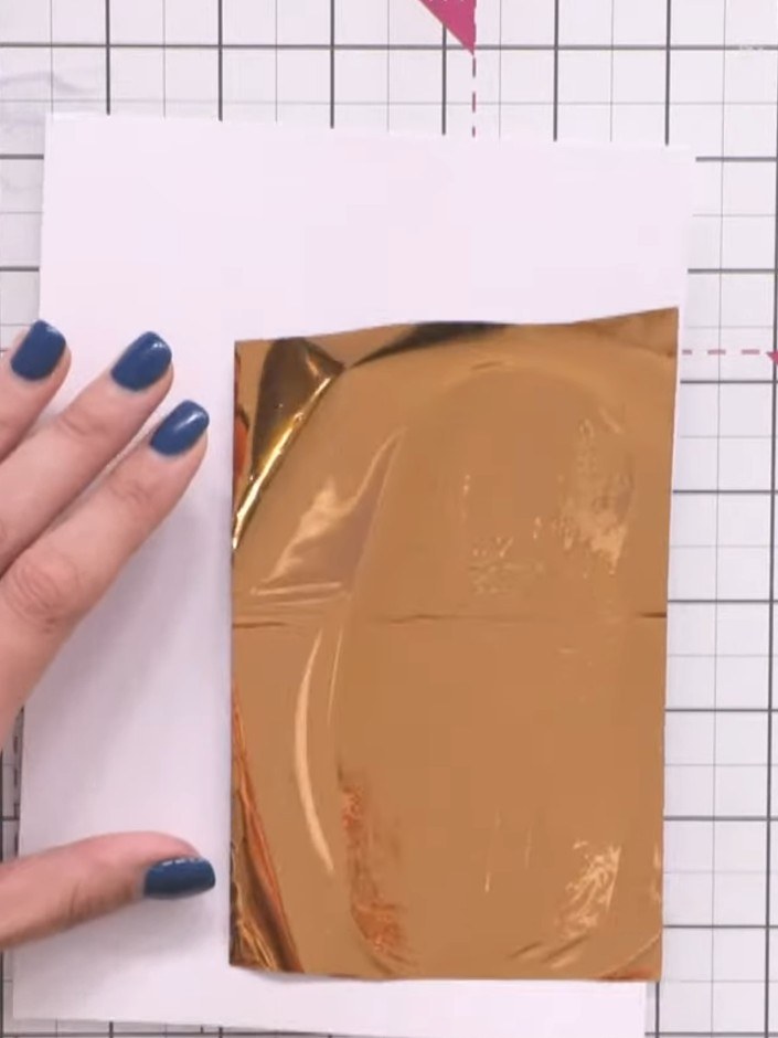 Passo 11: Gently burnish the foil with your finger, smoothing it over the stamped design to transfer the metallic finish