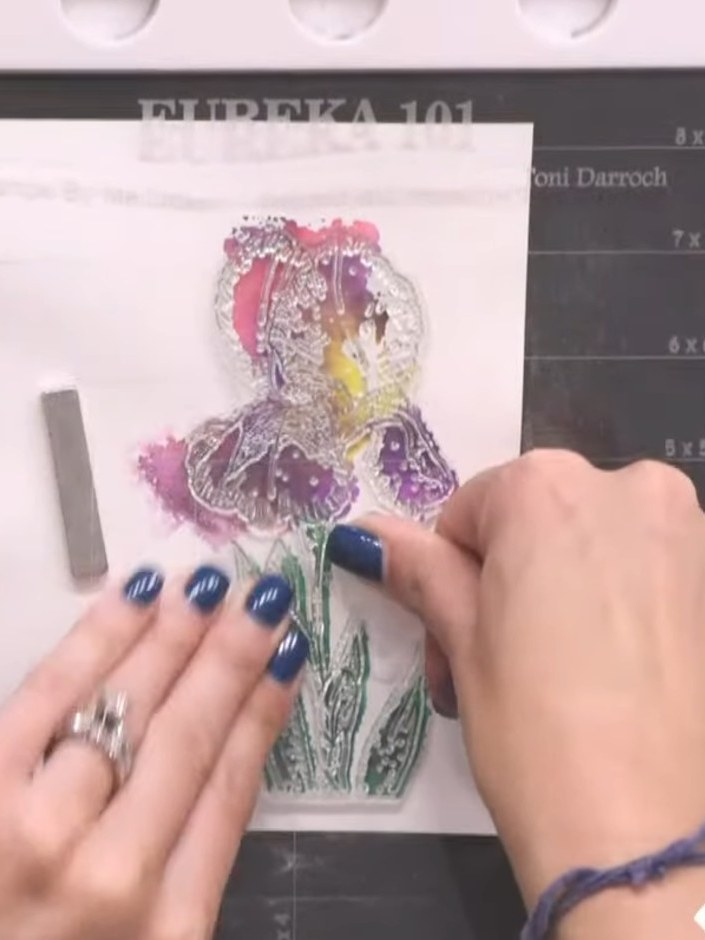Stap 9: Ink the detailed lamination stamp with the WOW sticky ink pad, stamping multiple times over the foiled iris de