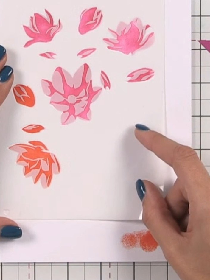 Passo 4: Apply orange ink through the second stencil, positioning it over the pink floral design to create a layered ef