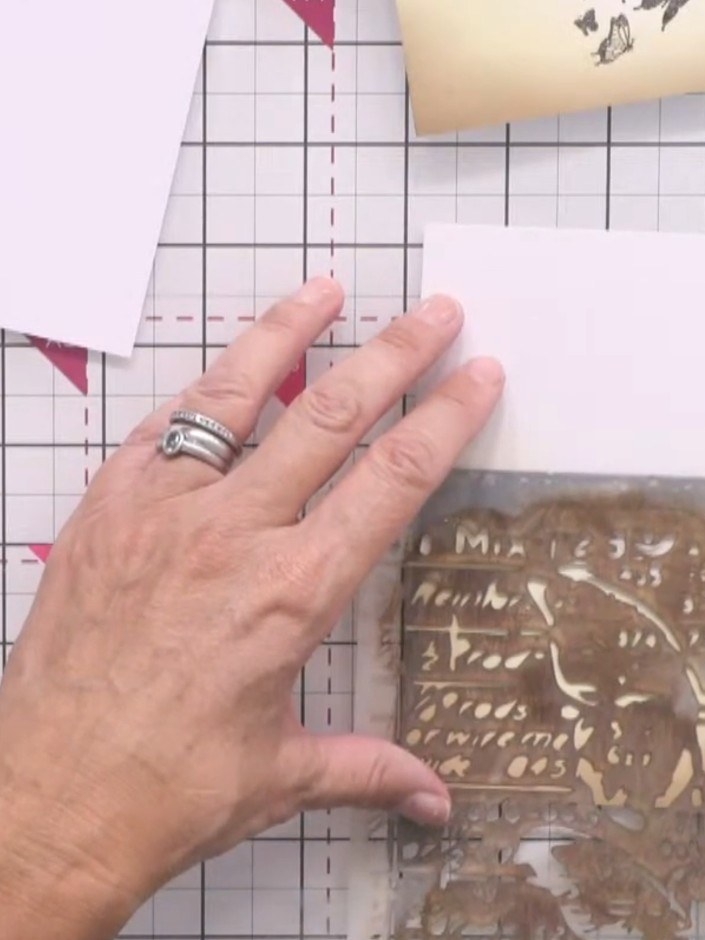 Passo 13: Use a butterfly stencil with ground espresso distress ink to add pale, distressed detail to the bottom panel. 