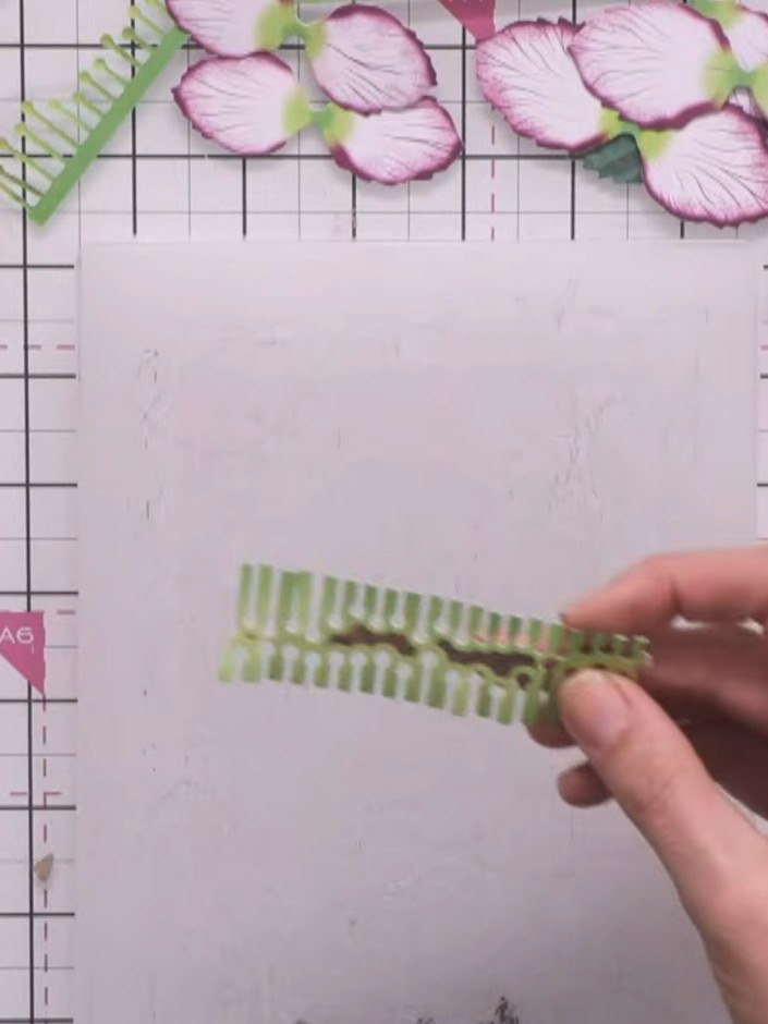Step 6: Position the two green leaves beneath the layered flowers, angling them naturally to frame the bloom. Place on