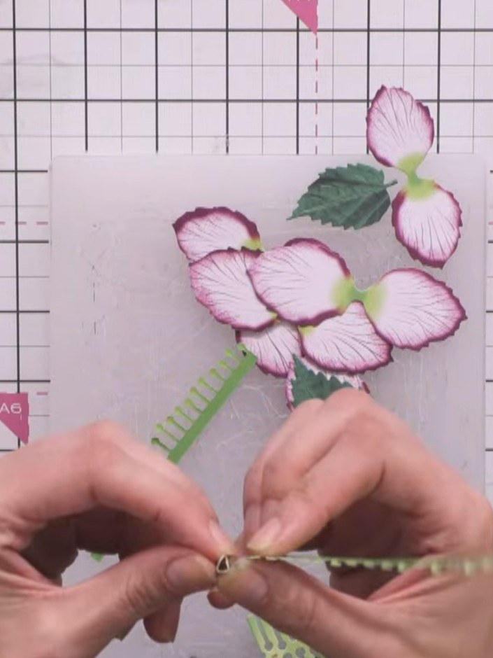 Step 7: Take the small sprigly element and roll it tightly. Secure the rolled piece in the centre of the hellebore flo
