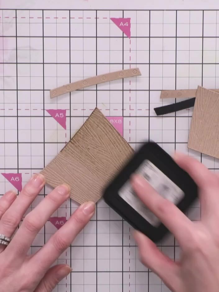Step 10: Distress the wooden crate pieces by swiping a black ink pad directly across the embossed surface to pick up th