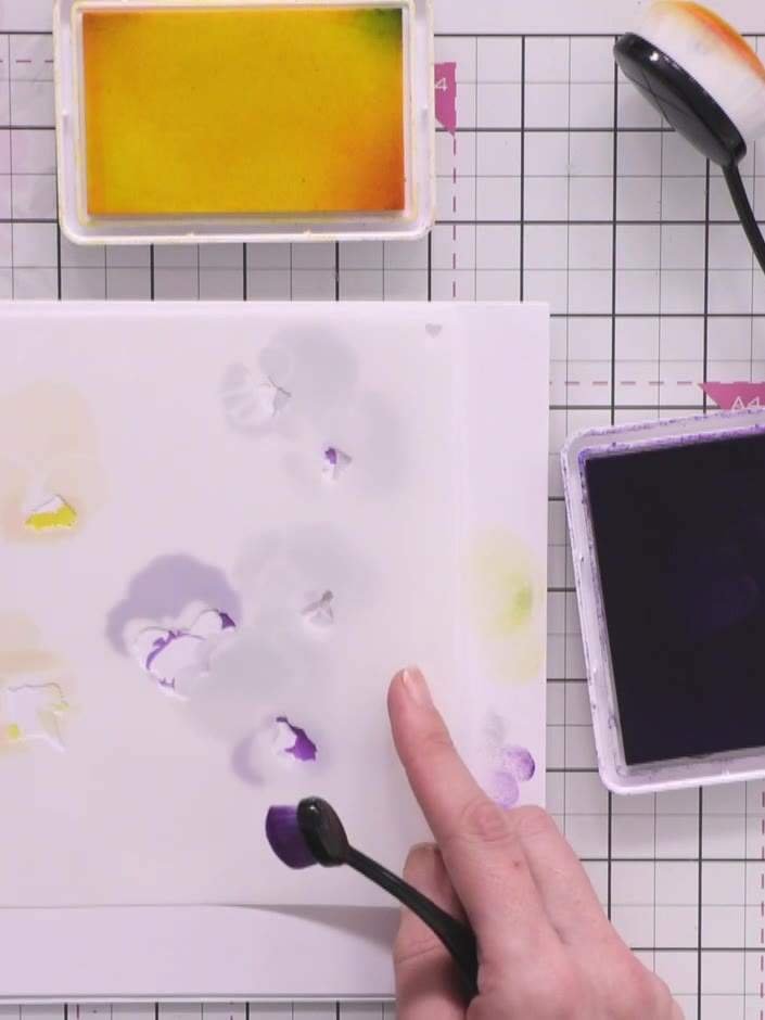 Step 5: Continue with stencil number three, applying purple and yellow ink colours to build up the pansy formation. Us