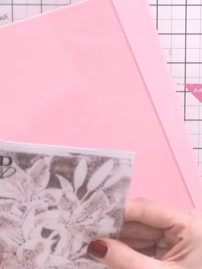 Step 4: Place your pink card stock over the inked and water-sprayed embossing folder. Close the folder firmly to trans