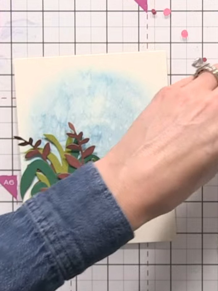 Step 11: Flick water droplets across the blue inked background using your fingers to create texture and soften the appe