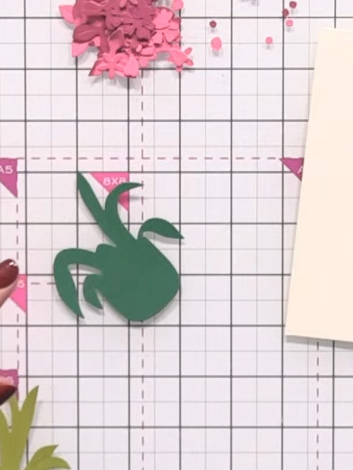 Step 6: Using glue, layer your first green foliage piece onto the card base, positioning it at the back of the arrange