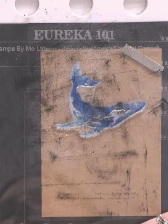 Step 5: Stamp the blue whale image directly over the white stamped base layer on the kraft card. The white underneath 