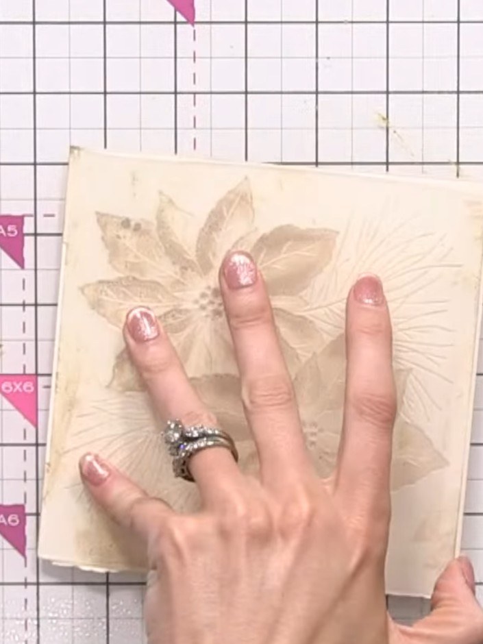 Step 6: Leg deinen vorbereiteten Cardstock in den Prägefolder und richte ihn mittig über dem Blumenmotiv aus.