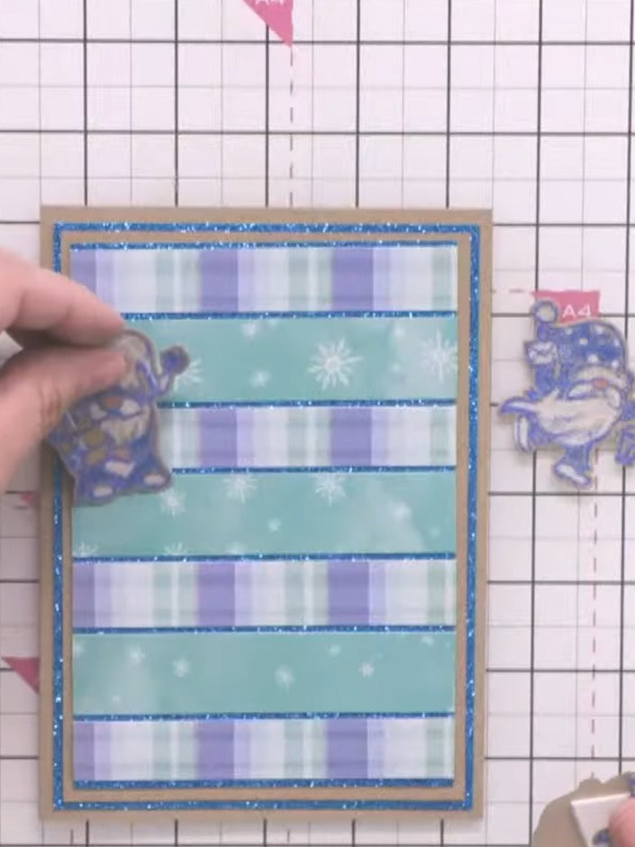 Step 10: Befestige den ausgestanzten Wichtel mit Schaumstoff-Klebeband auf dem gestreiften Panel – das sorgt für schöne Tiefe.