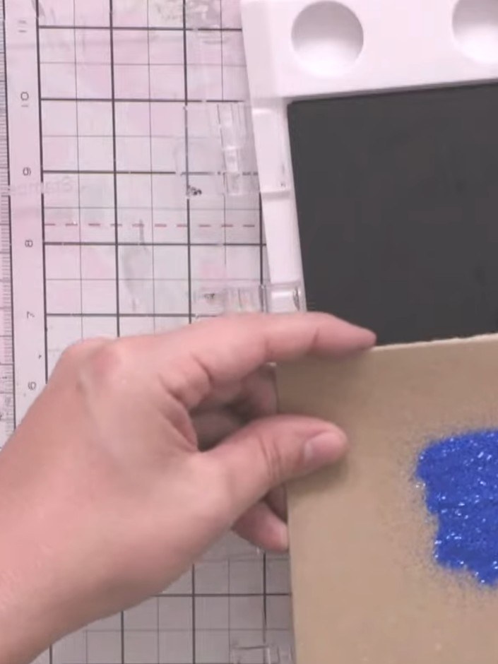 Step 3: Apply blue embossing powder to the stamped gnome image on the kraft card. Tap off the excess powder and heat e