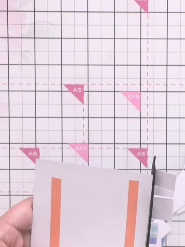 Step 8: Using scissors, trim the layered orange and white striped paper to match the size of your card base, removing 