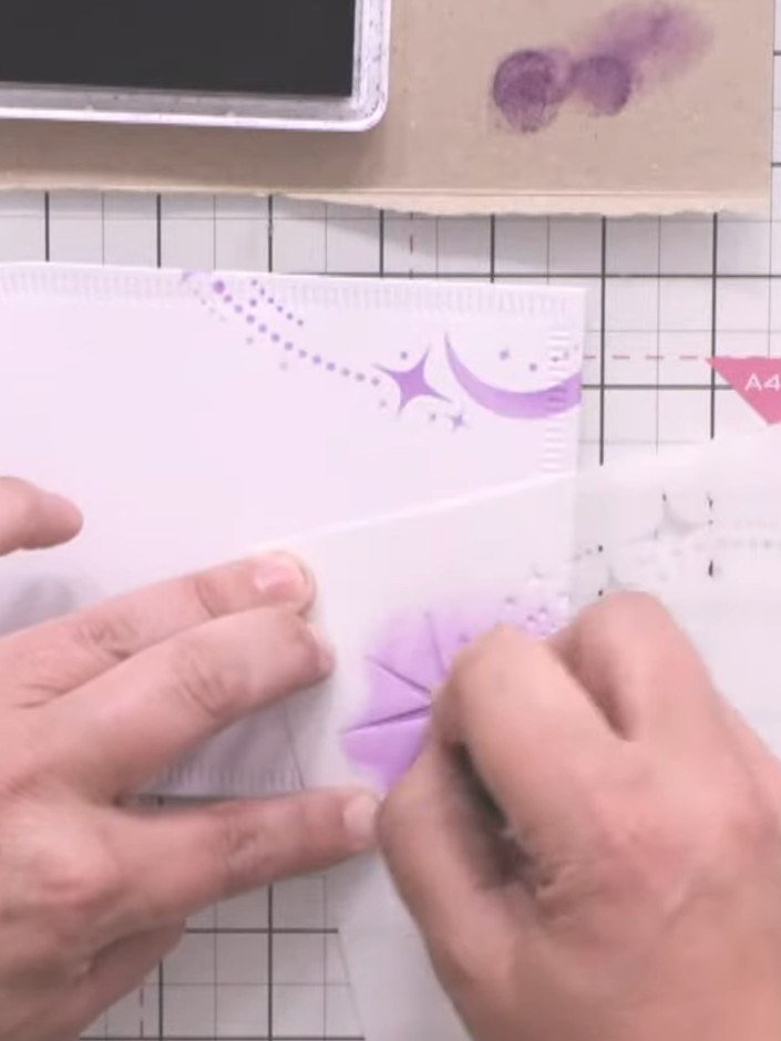 Step 4: Use the stencil to add purple candy cane and star motifs around the edges of your white card. Position the ste