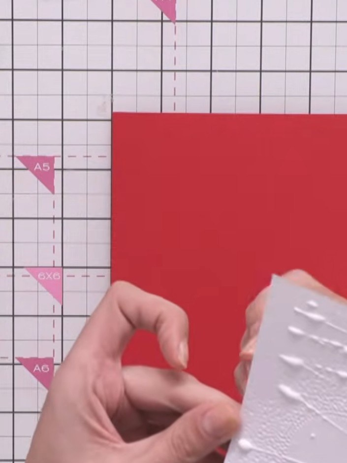 Step 3: Schneide ein Stück roten Cardstock zu, das etwas größer ist als dein geprägtes Panel. So entsteht ein Rahmen drumherum.