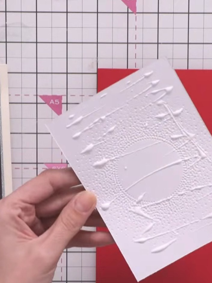Step 5: Setz das geprägte weiße Panel mit Abstandspads auf den roten Kartenrohling. So bekommt es schön Tiefe.