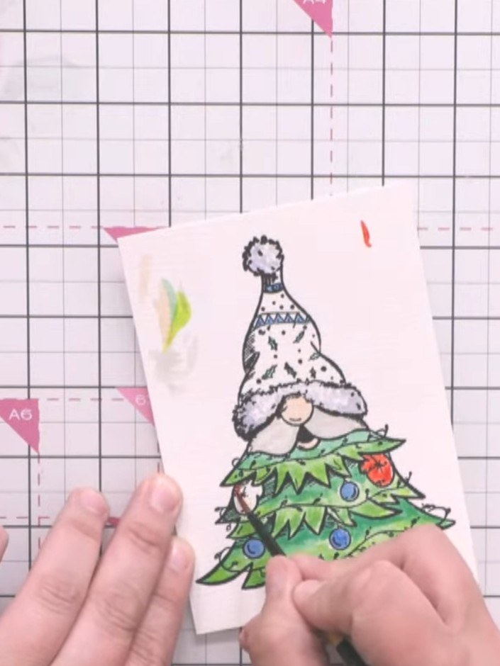 Step 4: Layer the die-cut coloured gnome topper onto a patterned paper background from the mystical Christmas pad. Pos