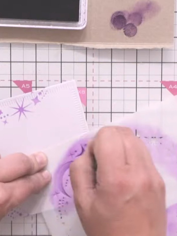 Step 5: Mount the nesting die-cut panel with the purple celestial design onto the shaped card base, aligning it carefu