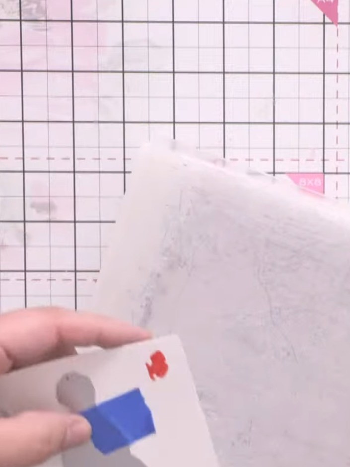 Step 9: Mount the die-cut gnome onto the layered background card using adhesive, positioning it centrally over the wat