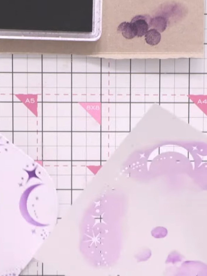 Step 5: Use a smaller nesting die from your set to cut shapes from the purple patterned paper with moons and stars. Po