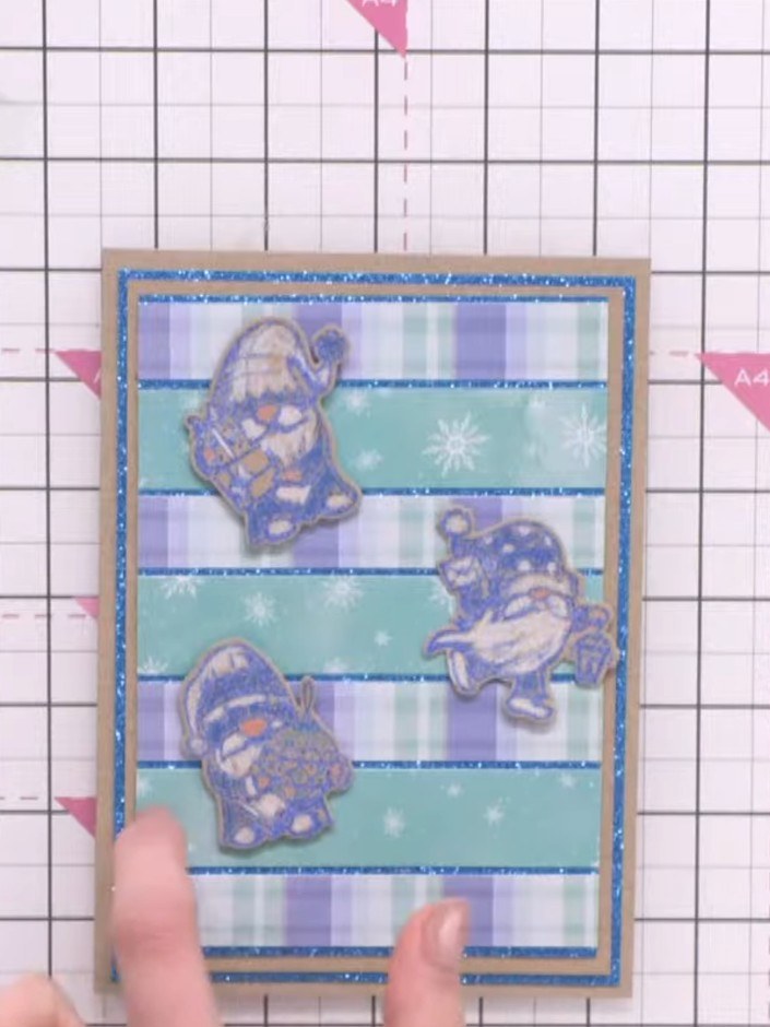 Step 6: Schichte die Papierstreifen über Glitzerkarton, sodass ein Streifenhintergrund entsteht – immer abwechselnd in Blau- und Rosatönen. 