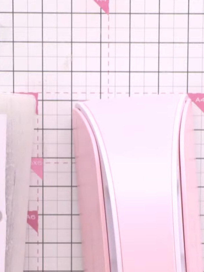 Step 2: Falze die obere Kante eines der ausgestanzten rosa Teile mit einem Falzwerkzeug auf deiner Bastelmatte.