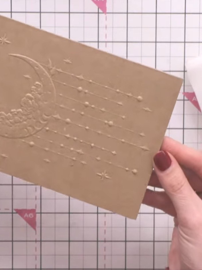 Step 2: Apply white pigment ink over the embossed details on the kraft card using a dabbing motion to highlight the te