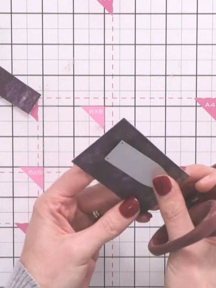 Step 6: Cut out the rectangular window from the dark grey die-cut frame piece using scissors. This creates a pocket fr