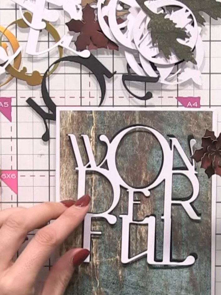 Step 4: Adhere the white 'WONDERFULL' word die-cut to the upper portion of your patterned paper card base. Position it