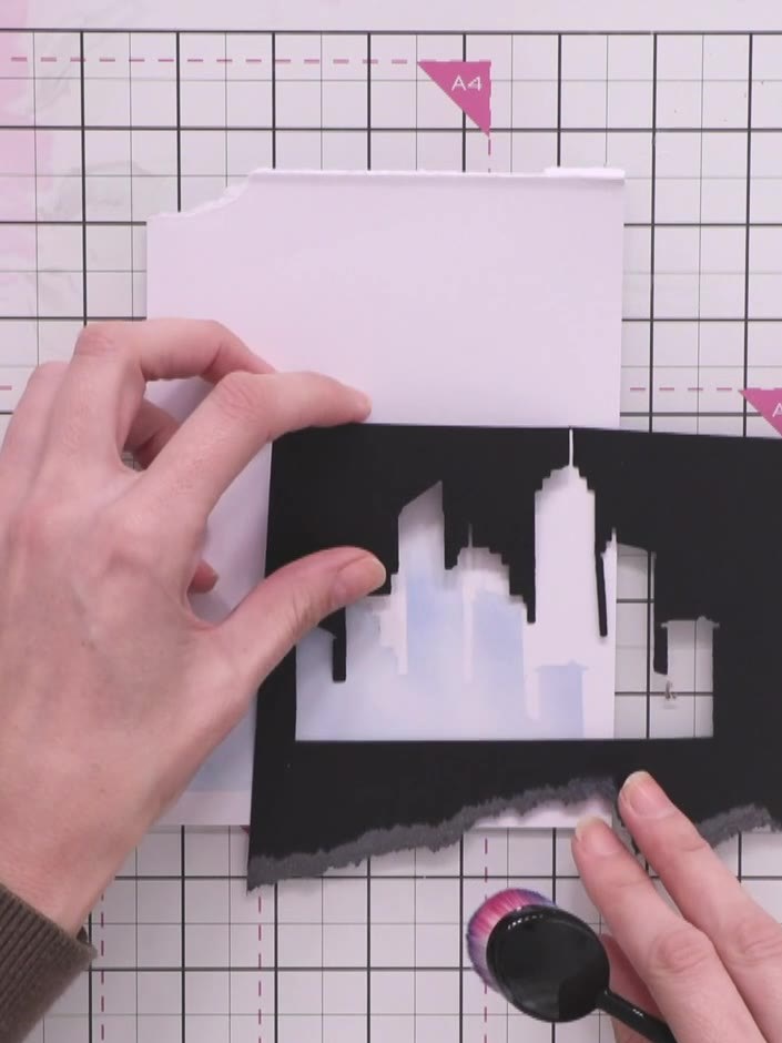 Step 7: Layer the black cityscape silhouette pieces at different heights on your card to create depth and dimension. P