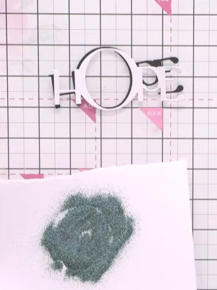 Step 3: Heat set the embossing powder with a heat gun, holding it over the glittery green area until the powder melts 