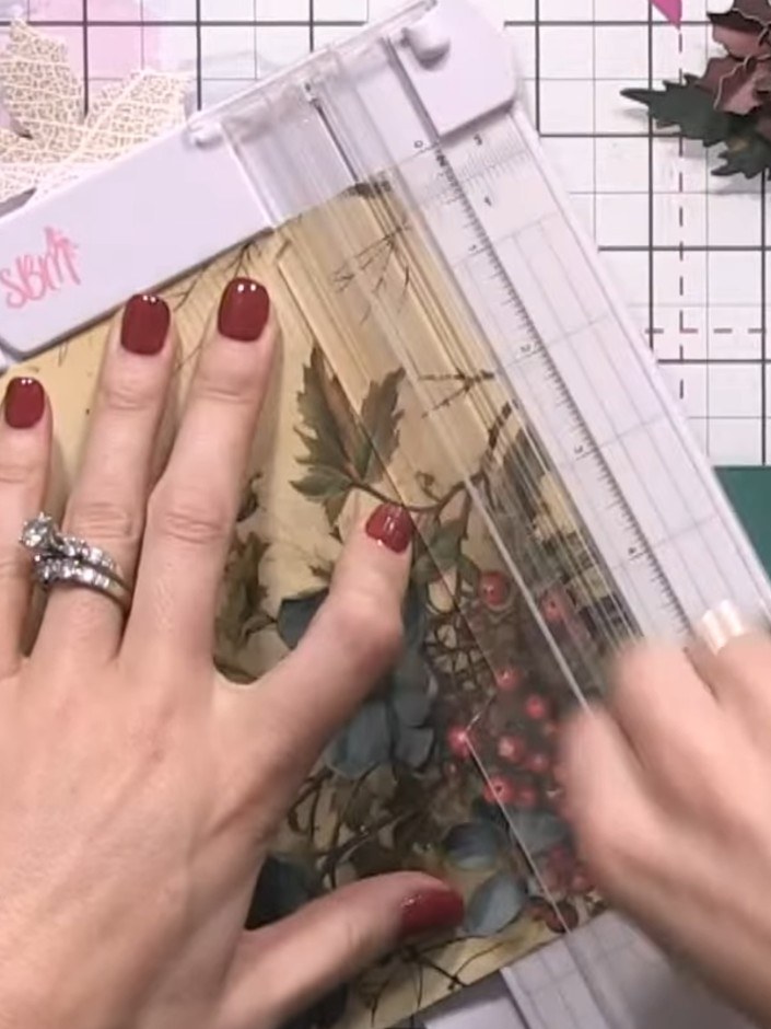 Step 7: Position the large brown pine cone on the card front as your main focal point. Place it over the floral patter