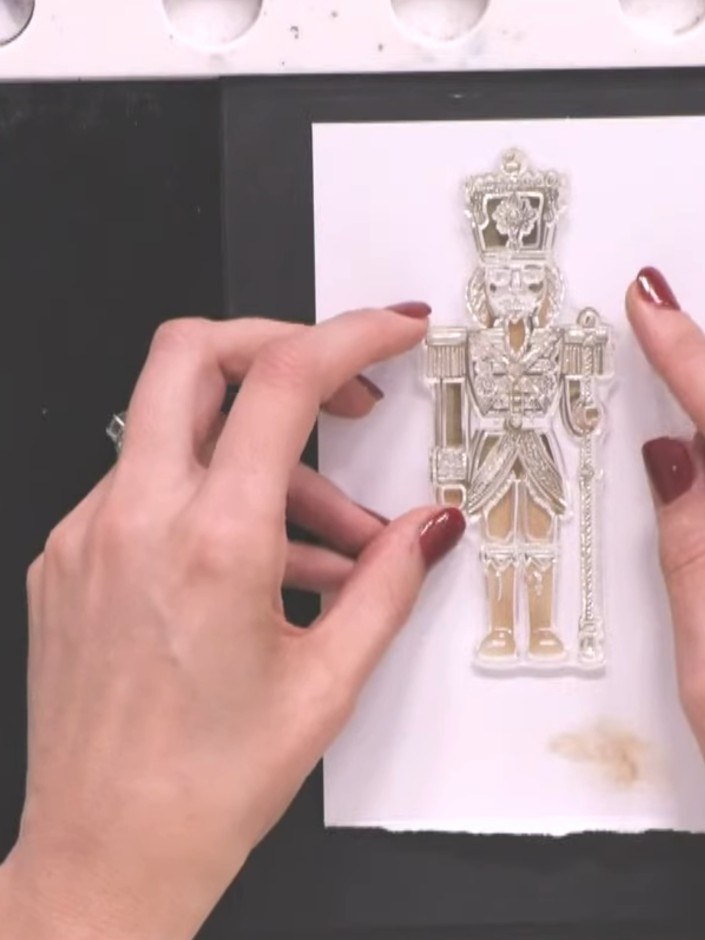 Step 8: Carefully remove the stamp from the card to reveal the detailed nutcracker image. Admire the layered effect cr
