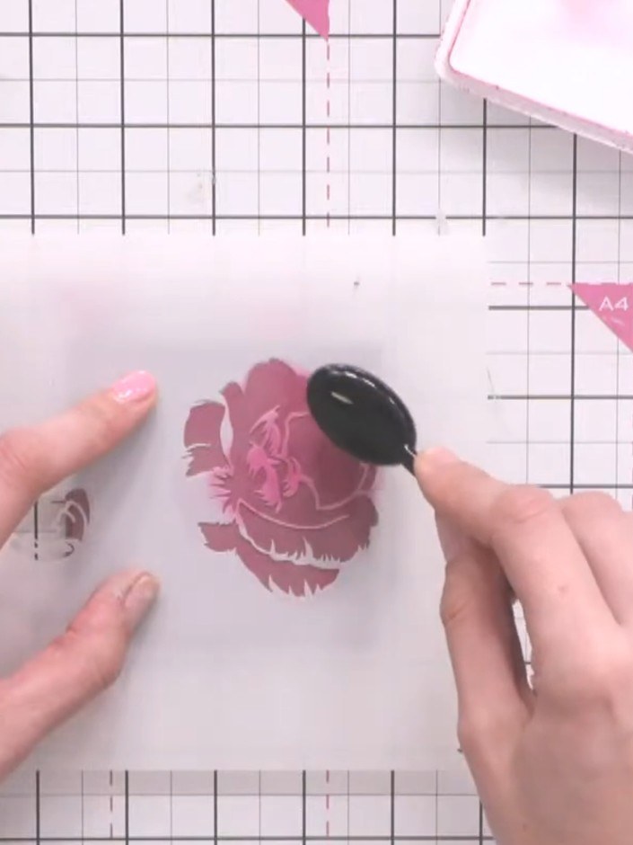 Step 8: Using the ink pad, tap over the second layer of the stencil to add more detail to the rose design on the coast