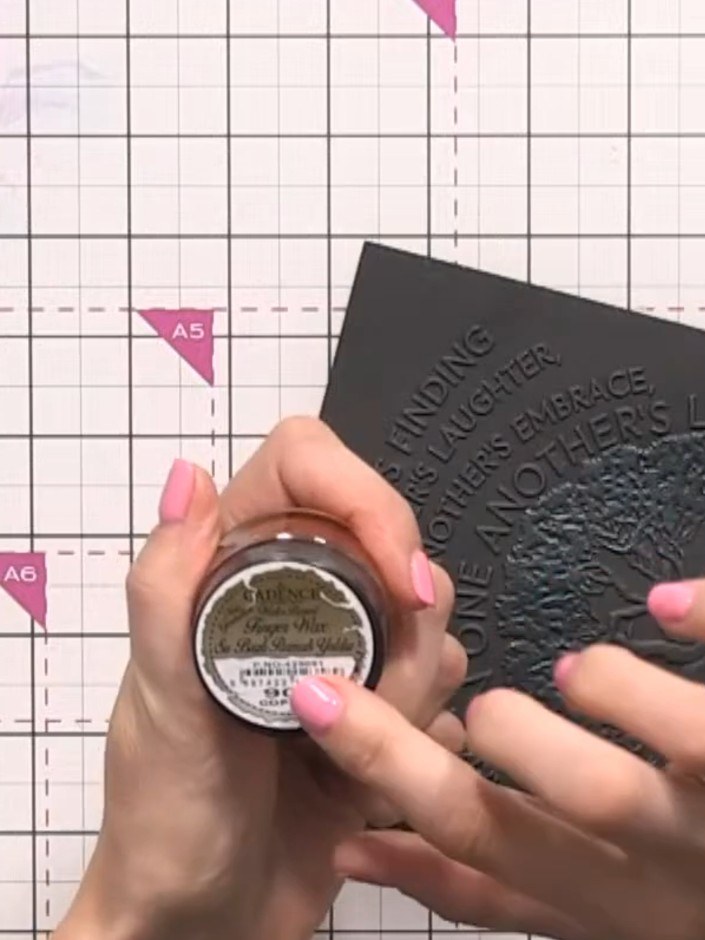 Step 5: Select copper gilding wax and apply it to the back or edges of the embossed design on the black card. Use your