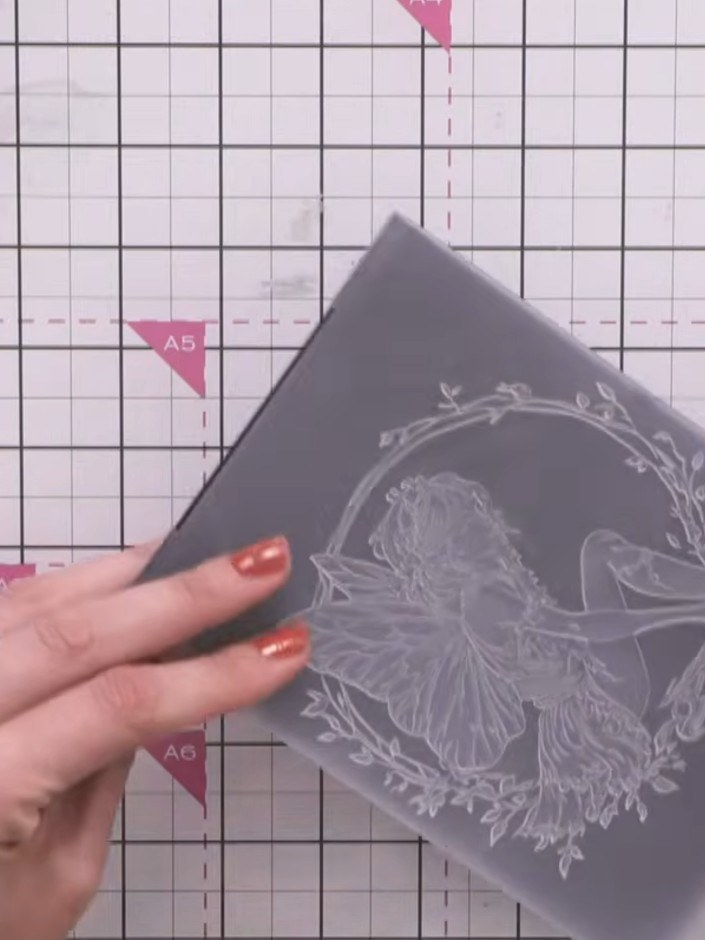 Step 1: Leg ein Stück schwarzen Cardstock so in den Prägefolder, dass die erhabene Seite des Motivs nach oben zeigt.