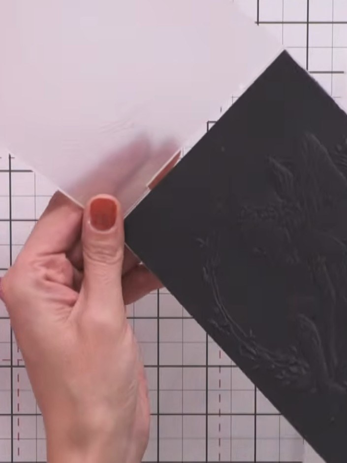 Step 4: Tap a white pigment ink pad gently onto the embossed design on the black card, focusing on the fairy's body, w